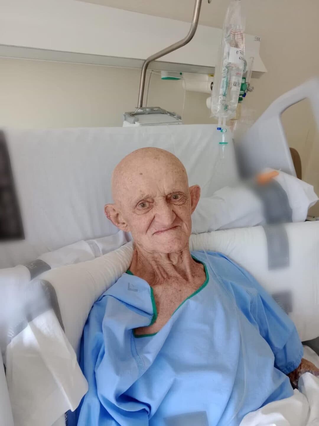Un hombre mayor al que acompañamos sonríe sentado en su cama del hospital